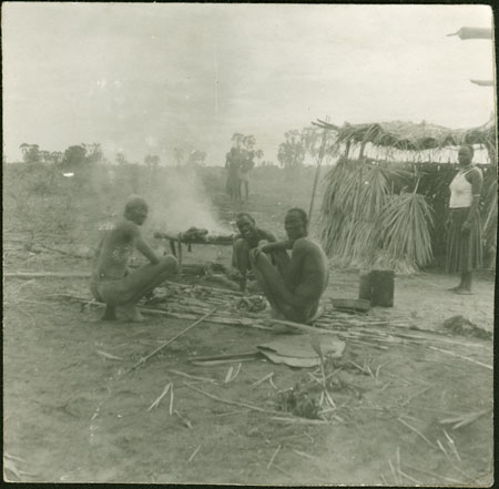 Mandari men preparing meat