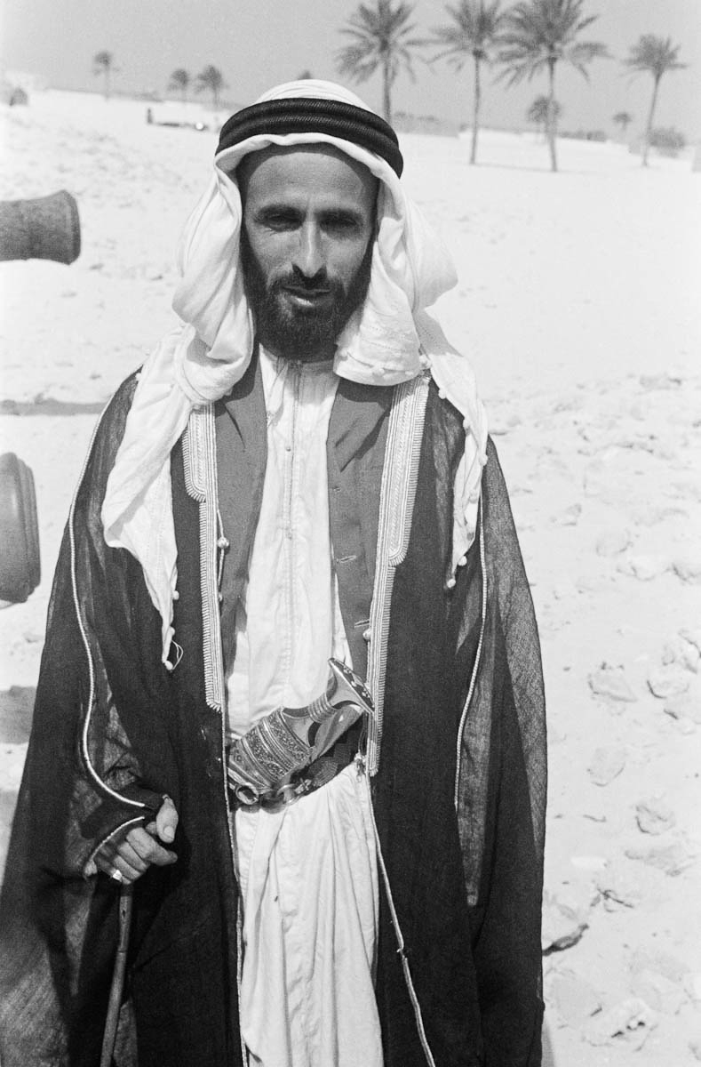 Three-quarter length standing portrait of Sheikh Shakhbut bin Sultan Al Nahyan outside Qasr Al Hosn fort in Abu Dhabi.