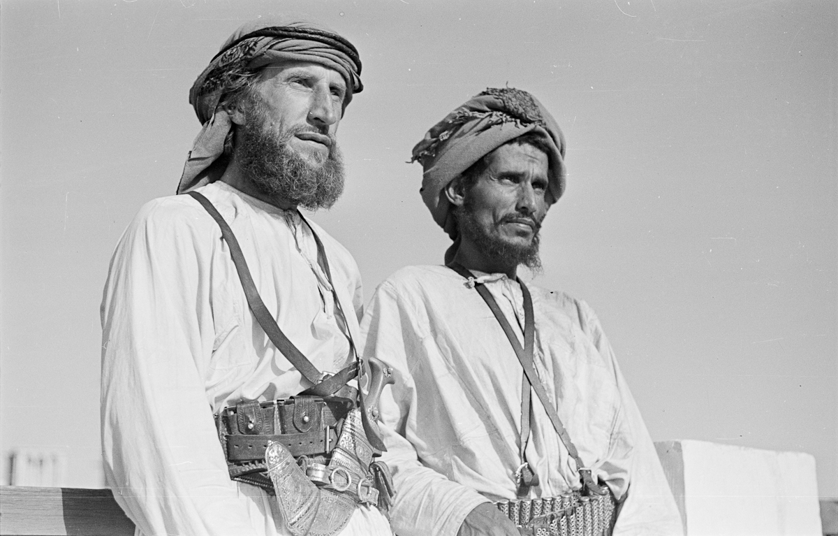 Standing half length portrait of Wilfred Thesiger and Musallim bin Al Kamam on a rooftop terrace in Dubai.