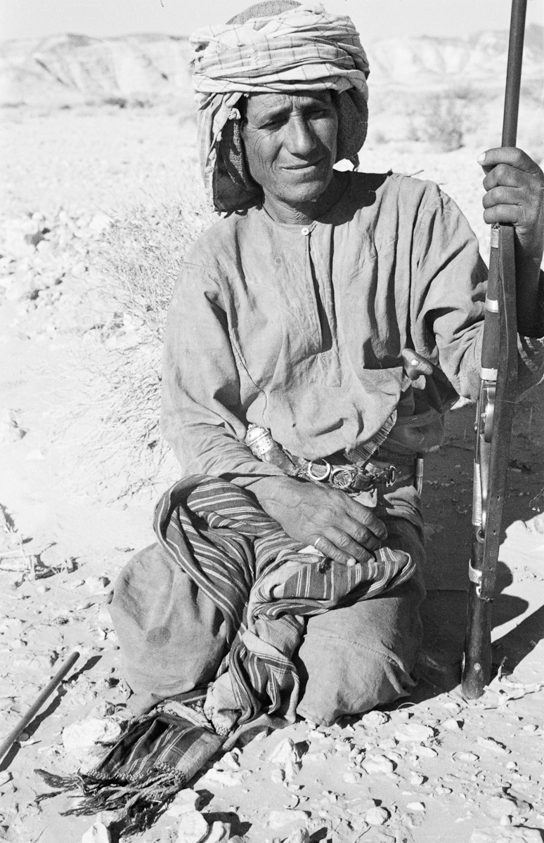 Seated portrait of Sultan bin Ahmad, a sheikh of the Sh'asha lineage of the Bayt Kathir Bedouin and a member of Wilfred Thesiger's travelling party, in the region between Wadi Rahnah and Al Maghar well.
