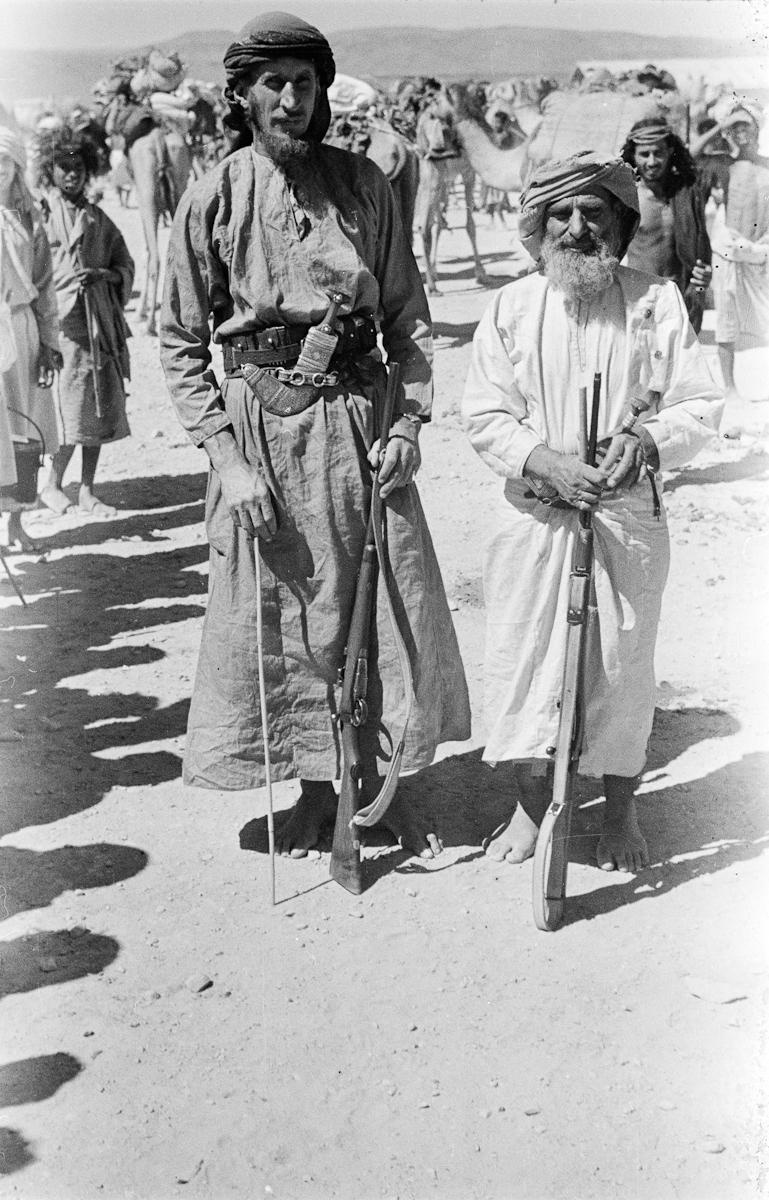 Portrait of Wilfred Thesiger (left) standing with Salim bin Kalut (right), one of his travelling companions. Salim bin Kalut (also known as Salah bin Kalut) is a sheikh of the Bayt Imani lineage of Rashid Bedouin. This portrait was taken at Salalah, at the beginning of the party's journey to Al Mukalla.