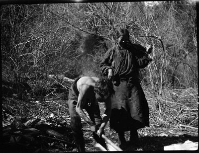 Boy chopping wood with his mother
